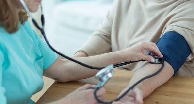 Medicinska sestra meri krvni tlak starejši osebi na domu